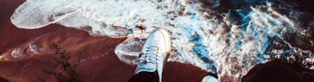 Feet dangling over a cliff overlooking a beach
