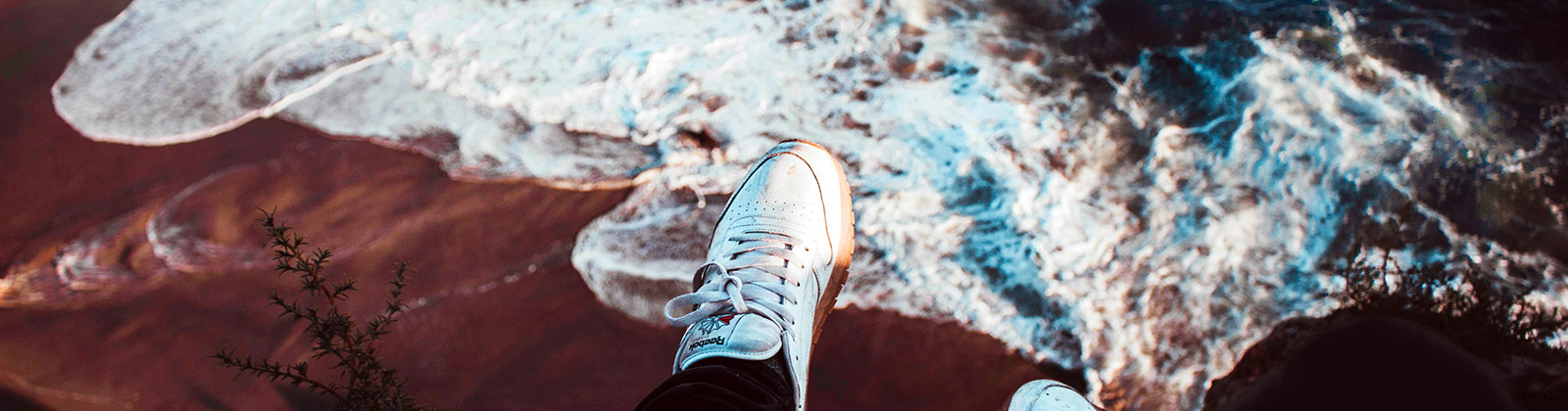 Feet dangling over a cliff overlooking a beach