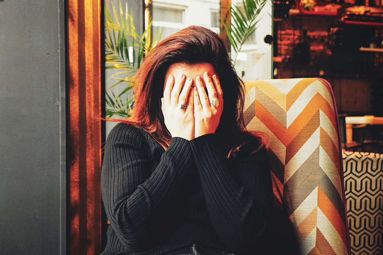 Woman sitting on a couch with her hands covering her face