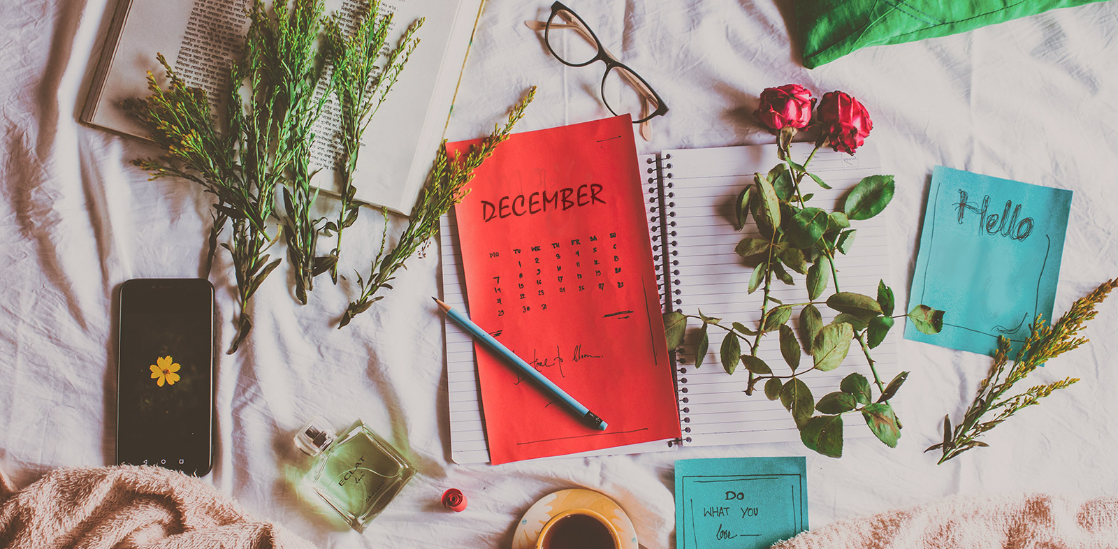 Miscellaneous items spread out including a calendar for December and a notebook for year end review and reflection