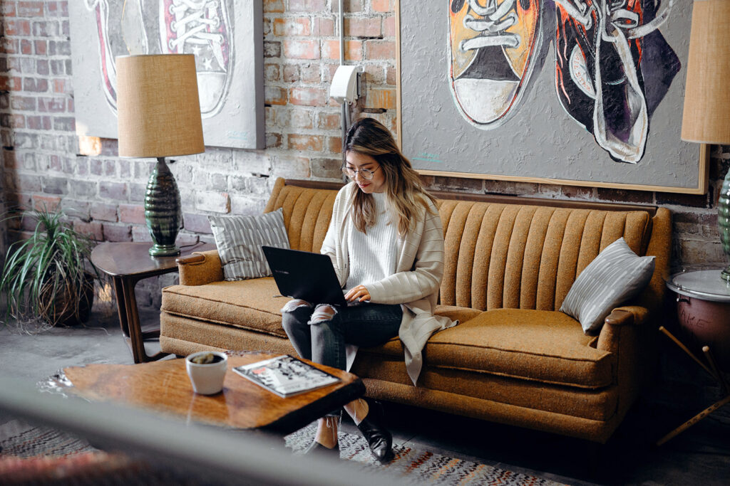 Woman sitting on couch typing on her laptop