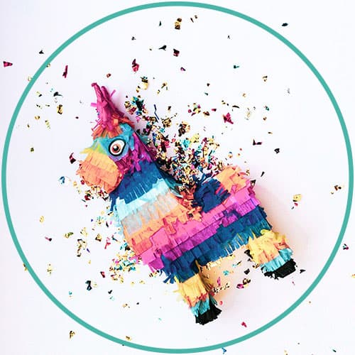 A colourful llama pinata with confetti sprinkled in the background